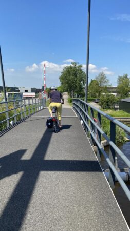 Frau von hinten auf Fahrrad über Brücke